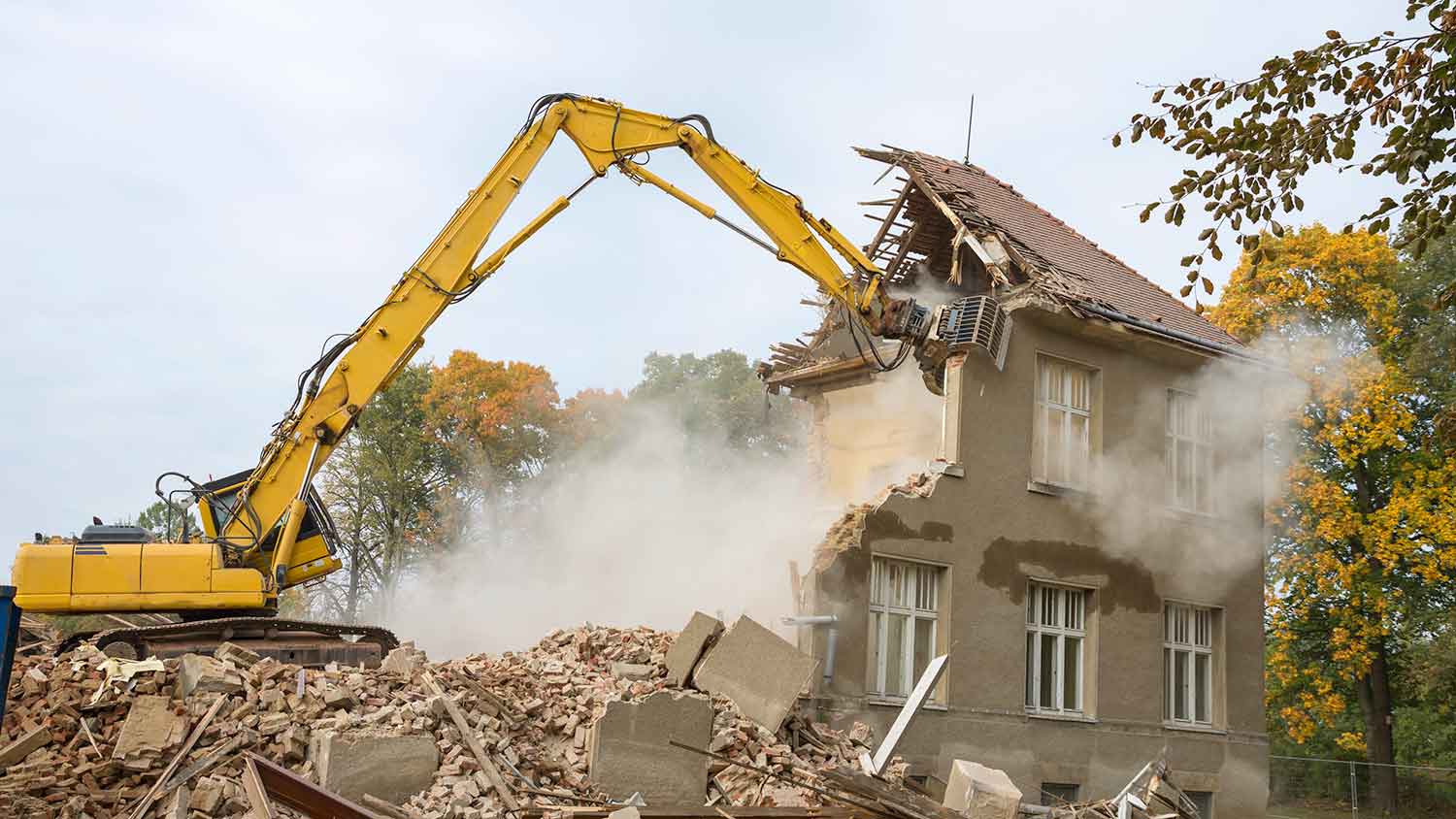 Professional using demolition machine to demolish an old house