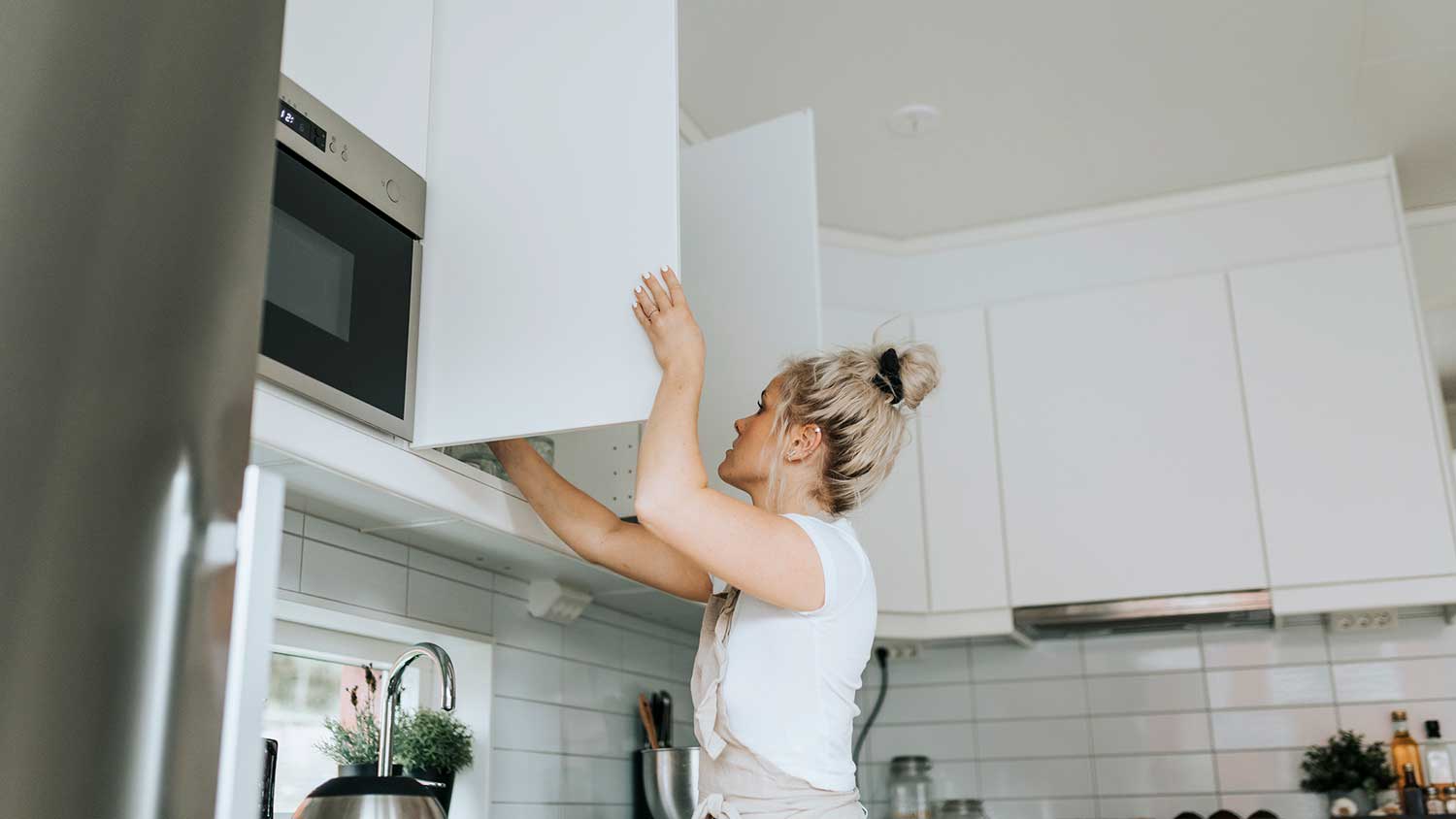 Woman in the kitchen opening cabinet door