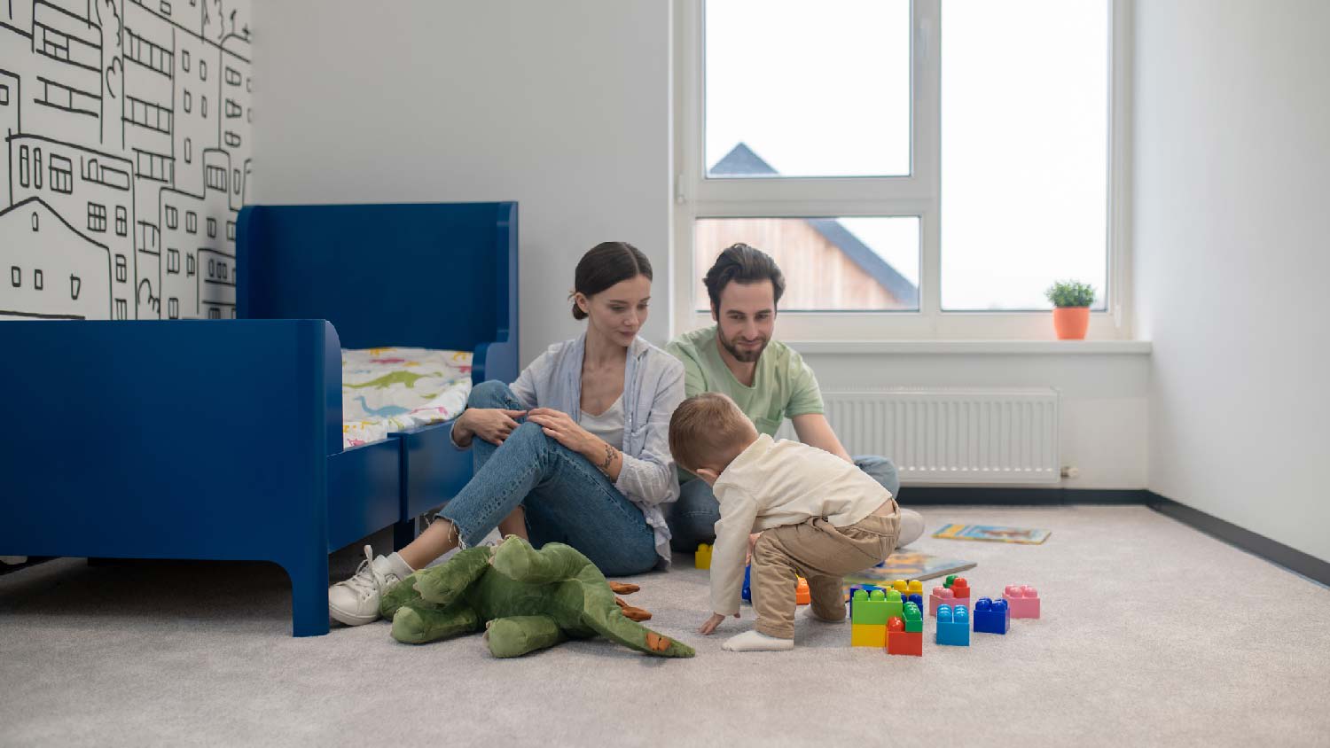 A family of three playing on the carpet