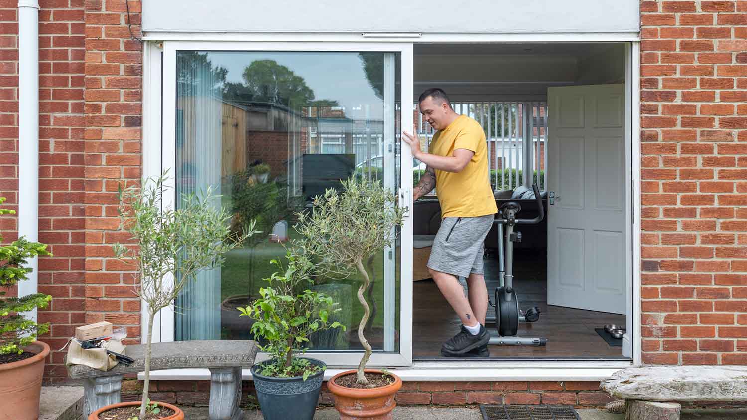 Man opening sliding patio door to let the fresh air in