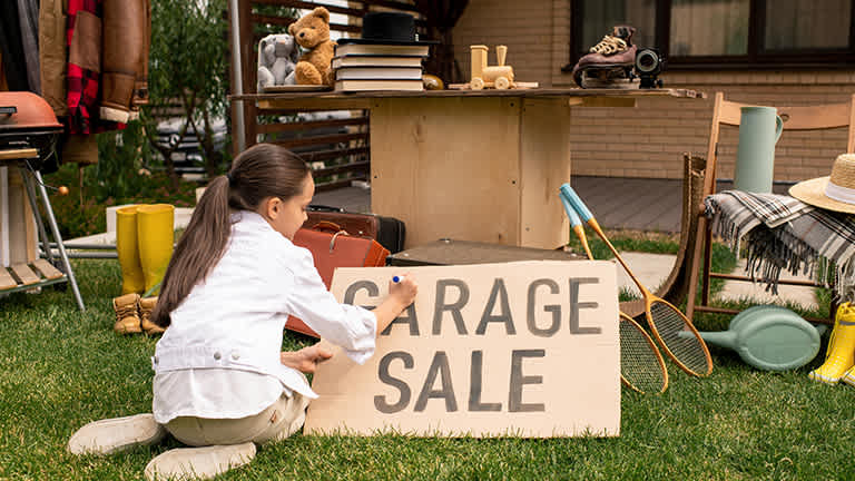 Little girl makes a garage sale sign