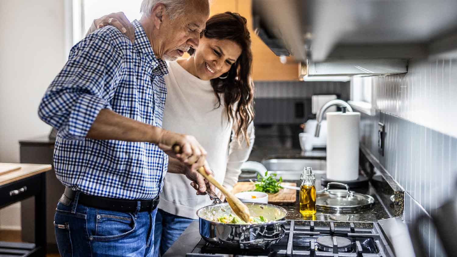 A senior couple cooking on a stove