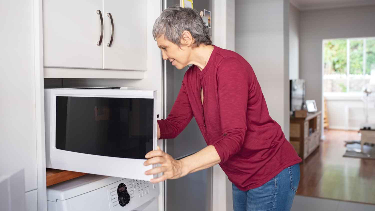 Woman opening microwave in the kitchen