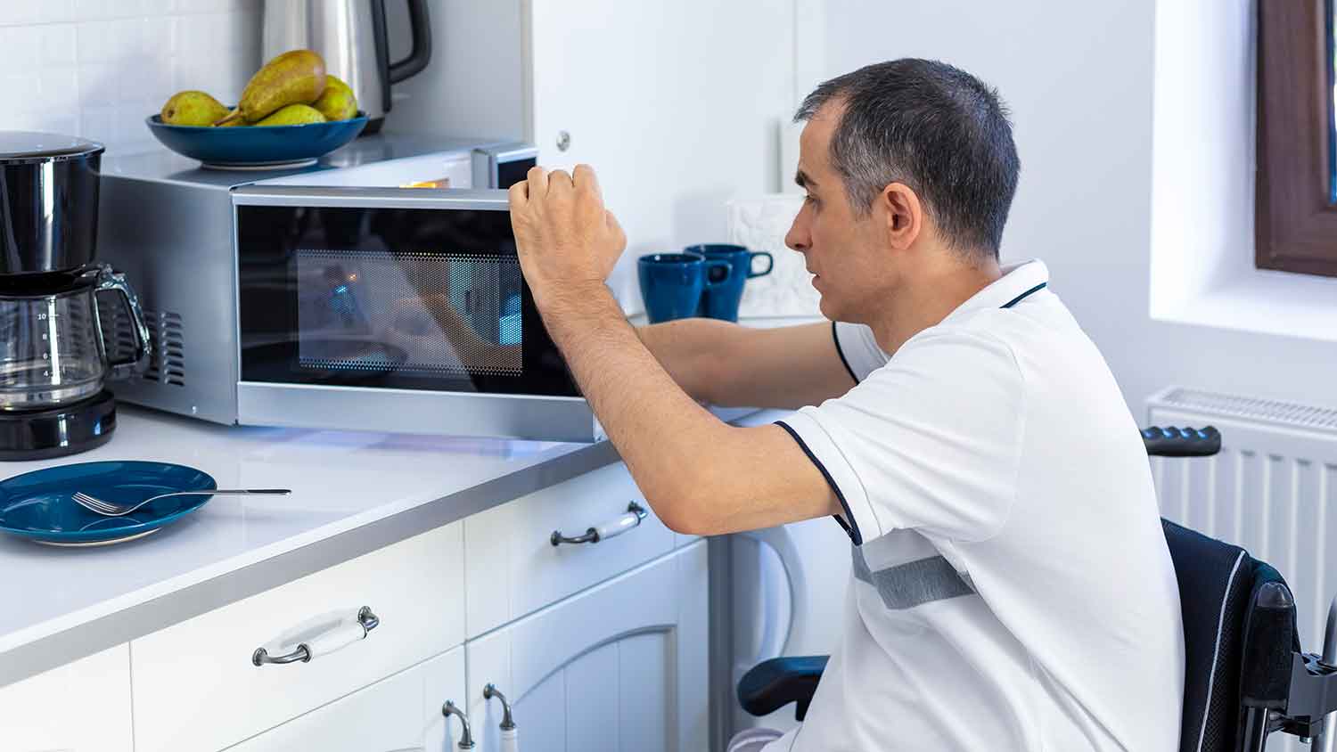 Man in the kitchen opening microwave door