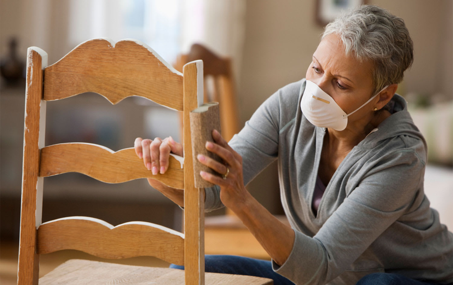 Woman sanding chair at home