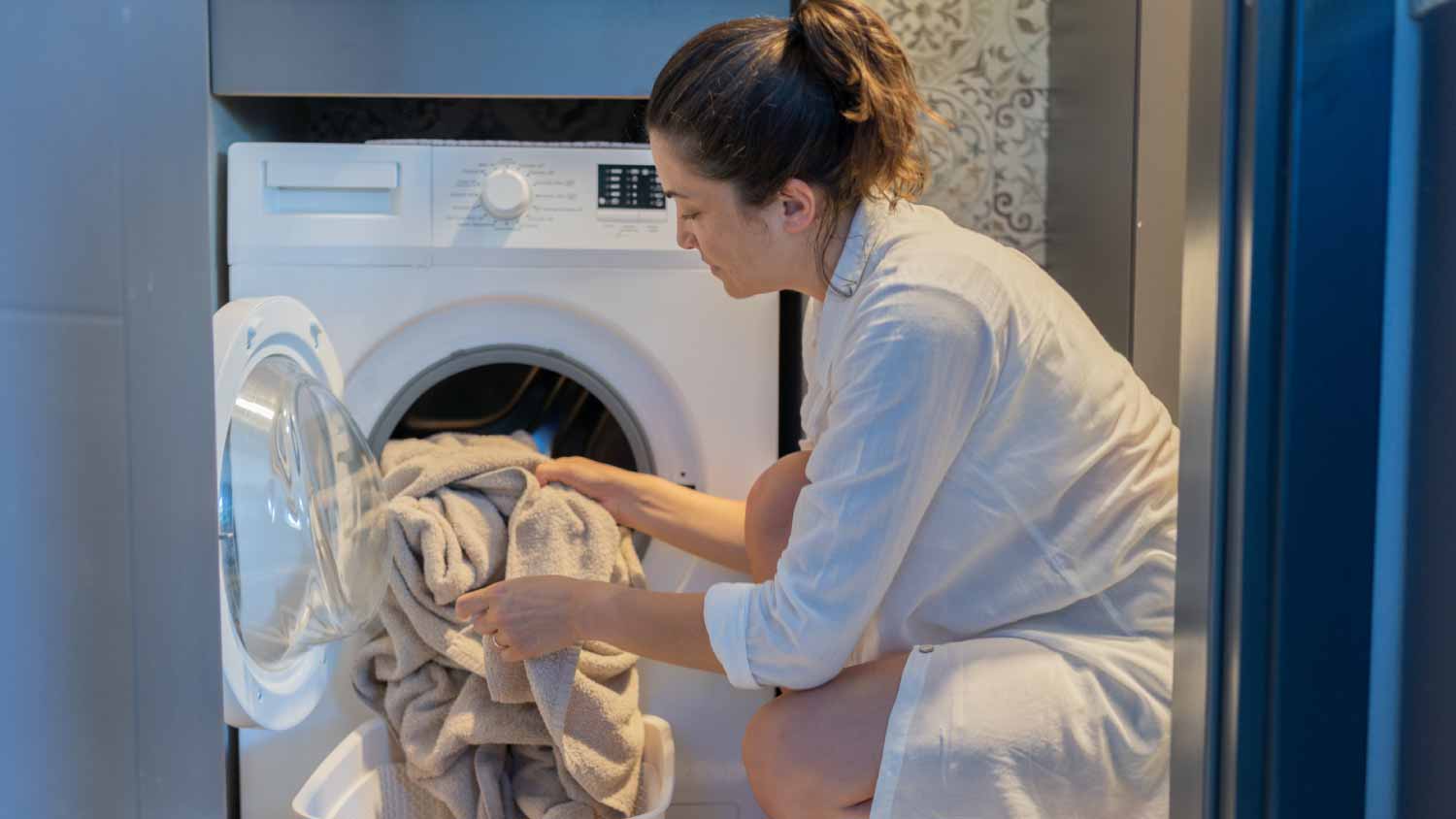 Woman loading clothes in washing machine