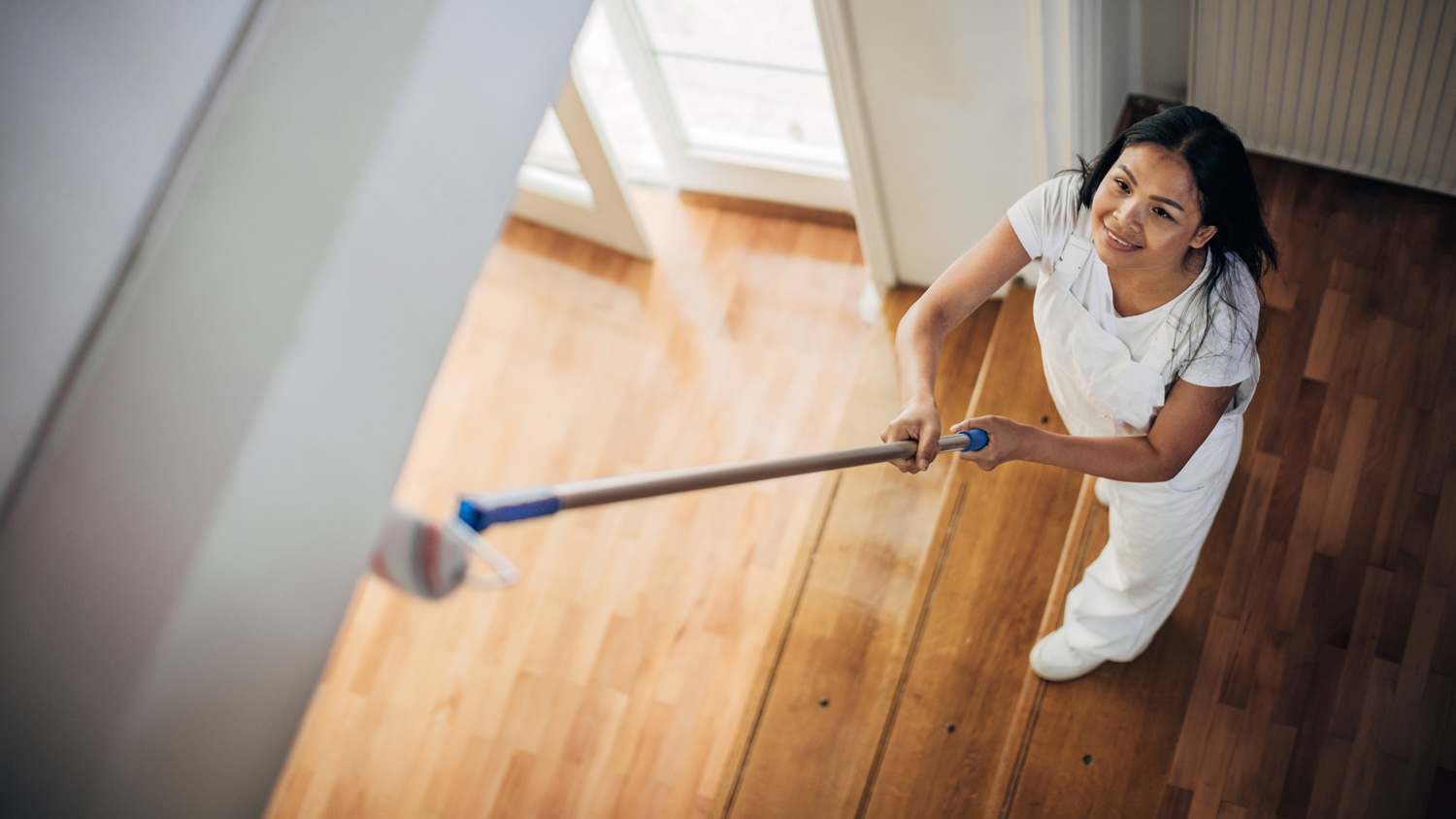 Woman painting ceiling with roller