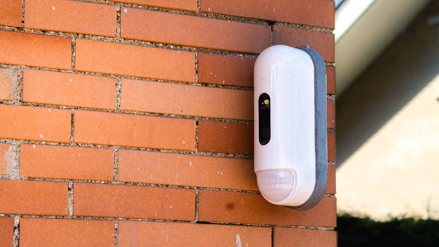 A motion detector installed on a red brick house