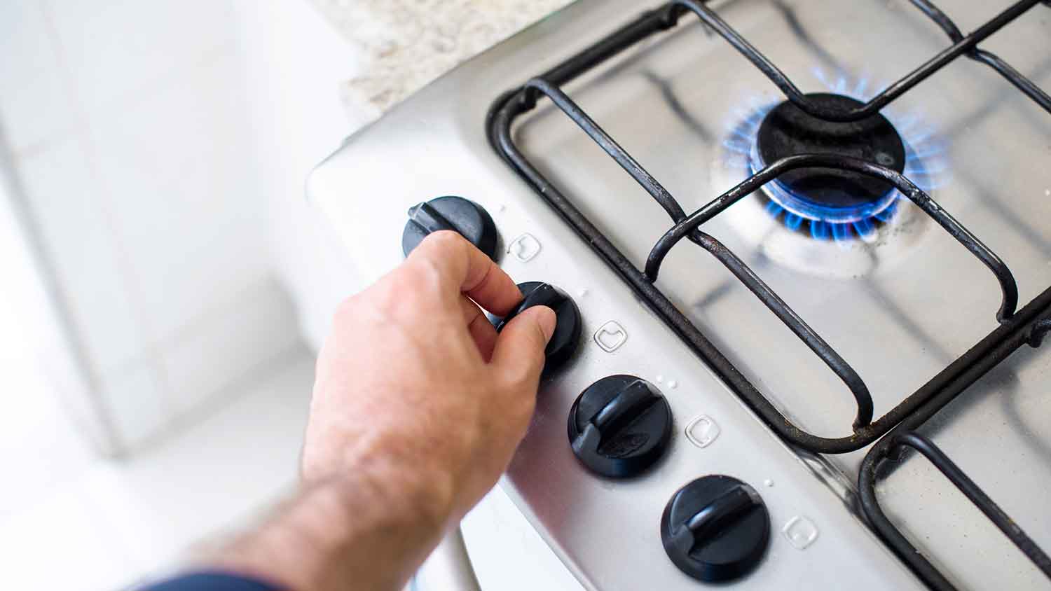 Person adjusting gas flame on a stove