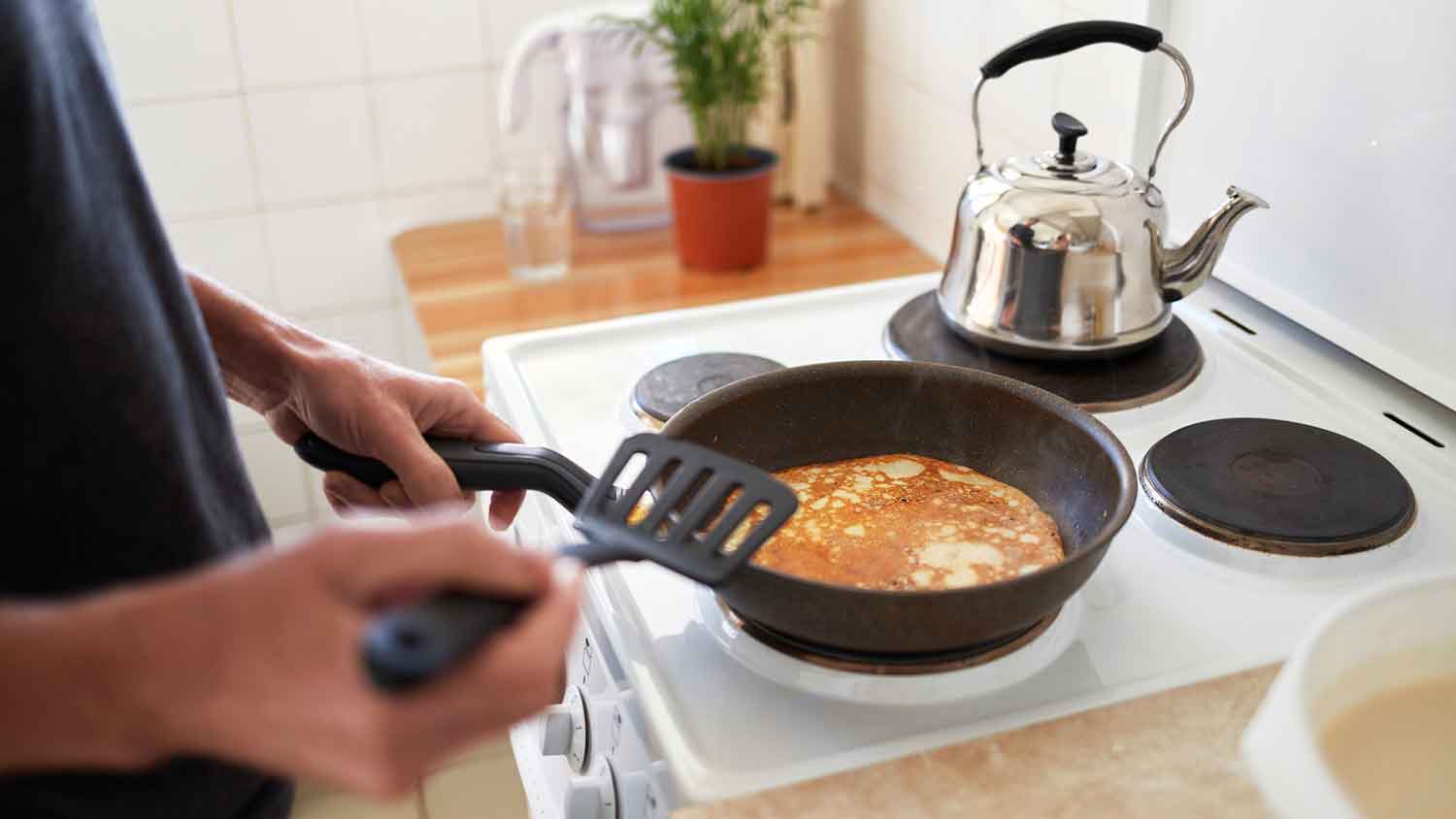 Person making pancakes on an electric stove