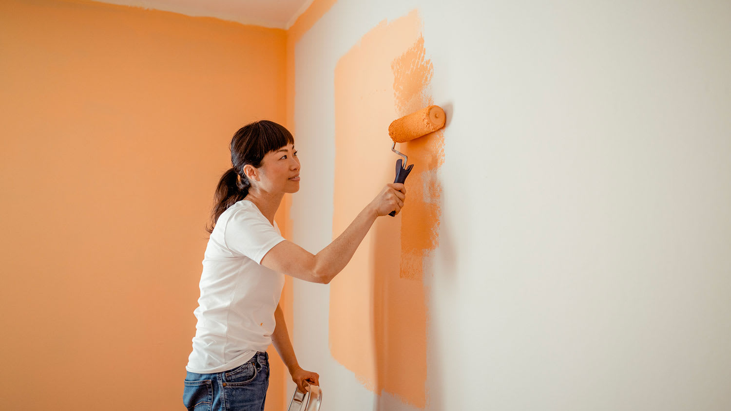 A woman painting a room with a roller