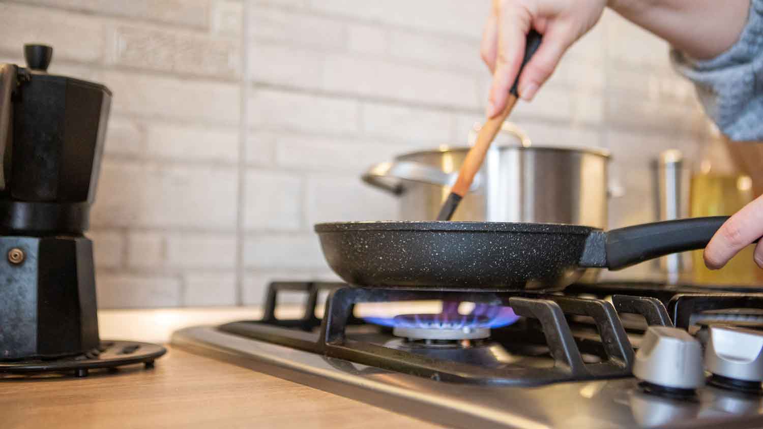 Closeup of a woman using gas stove to cook a meal