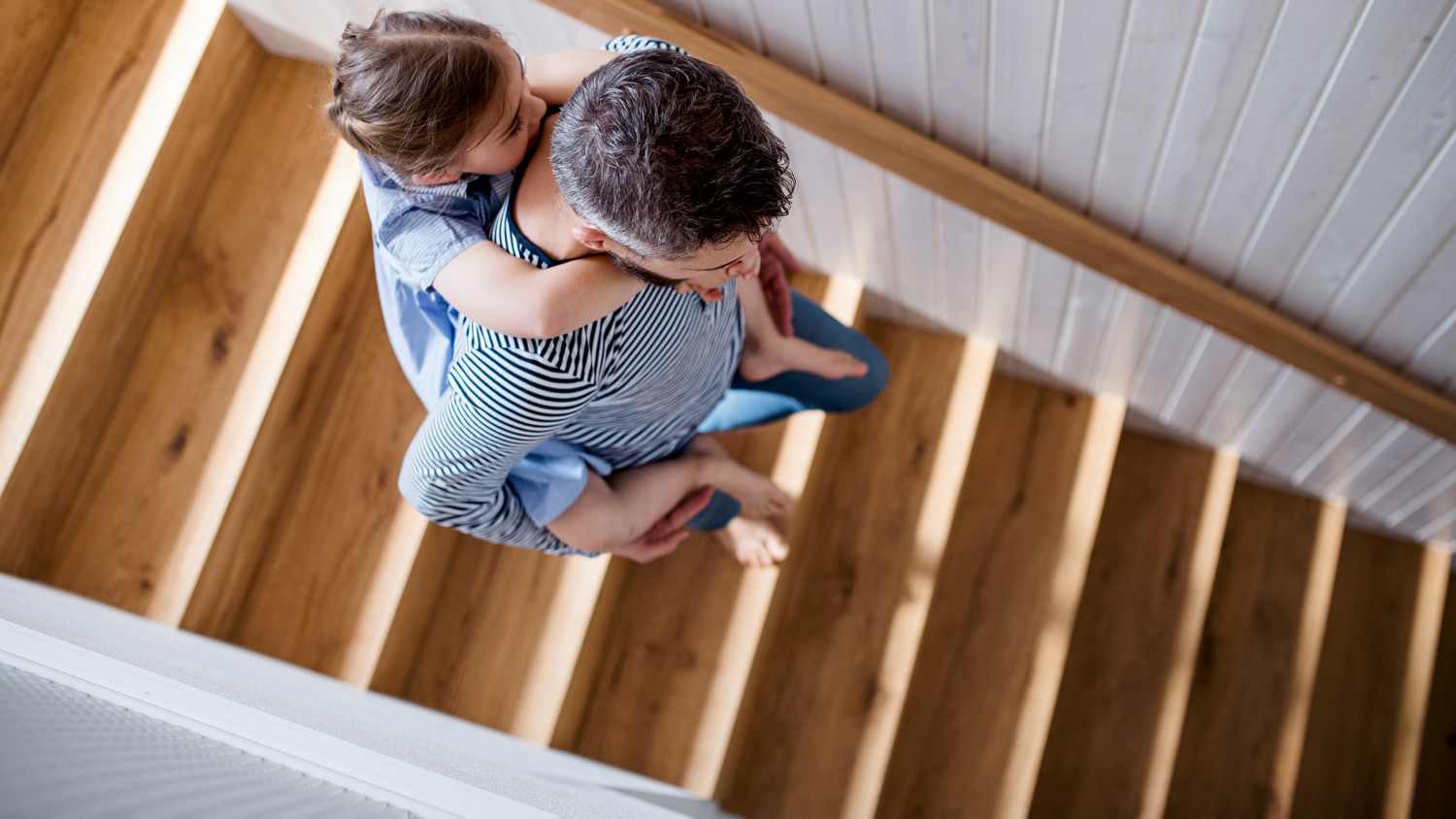 Dad holding daughter as they walk down the stairs