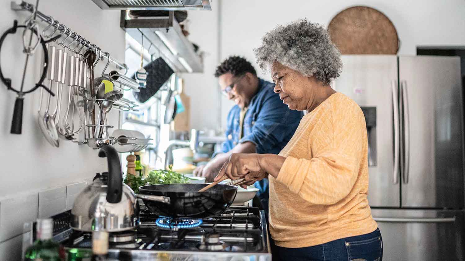 Mother and adult son cooking together at home