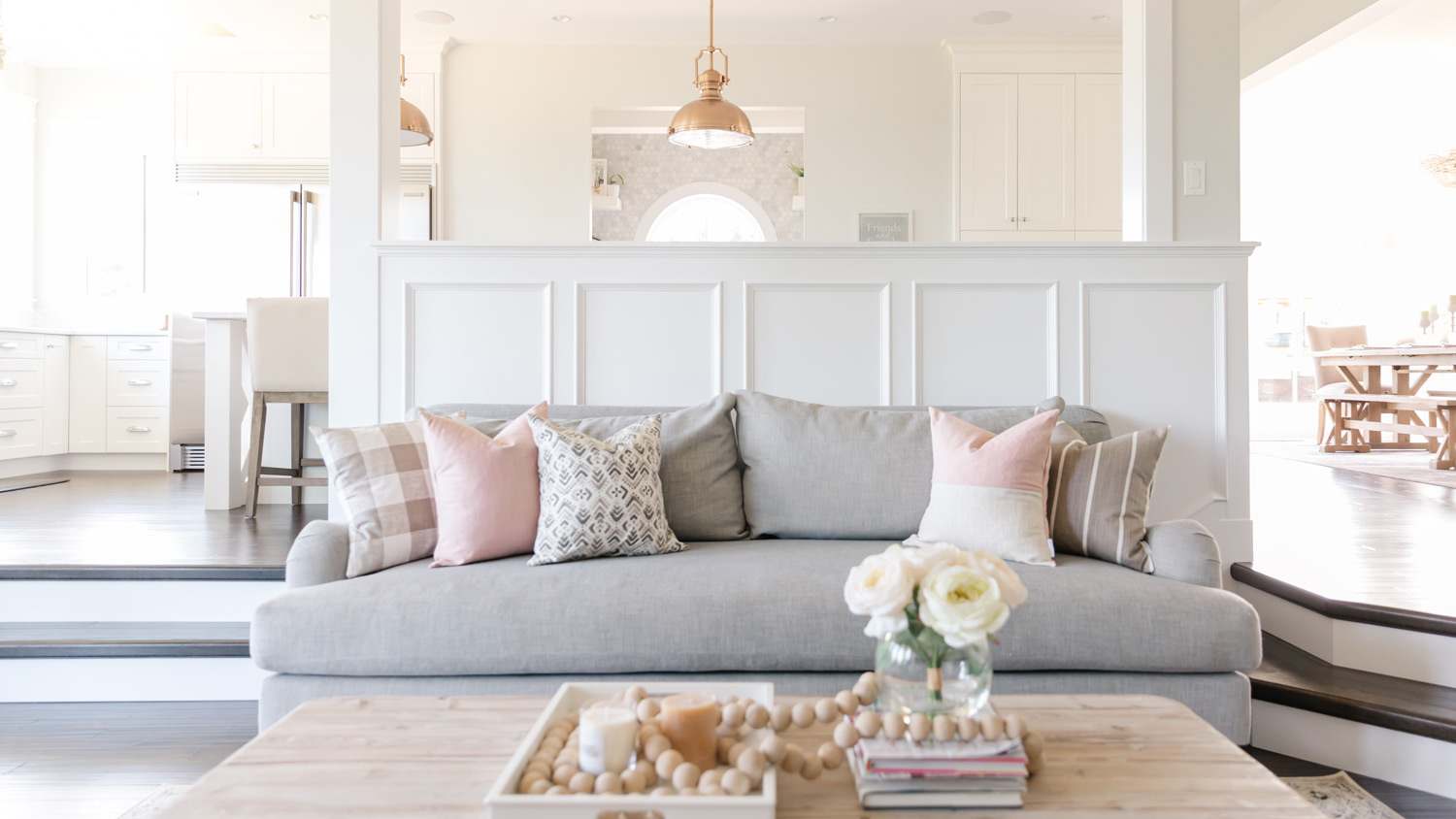 A bright sitting room with the kitchen in the background