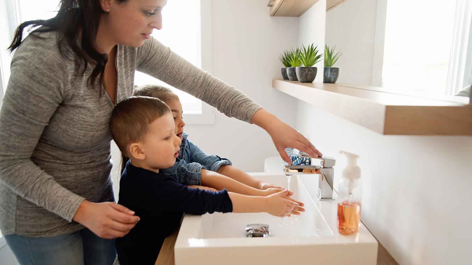 Mother and children washing hands in the bathroom