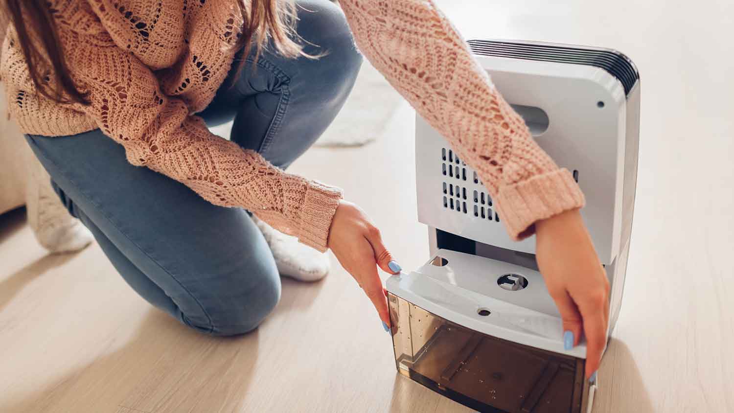 Woman changing water container of a dehumidifier