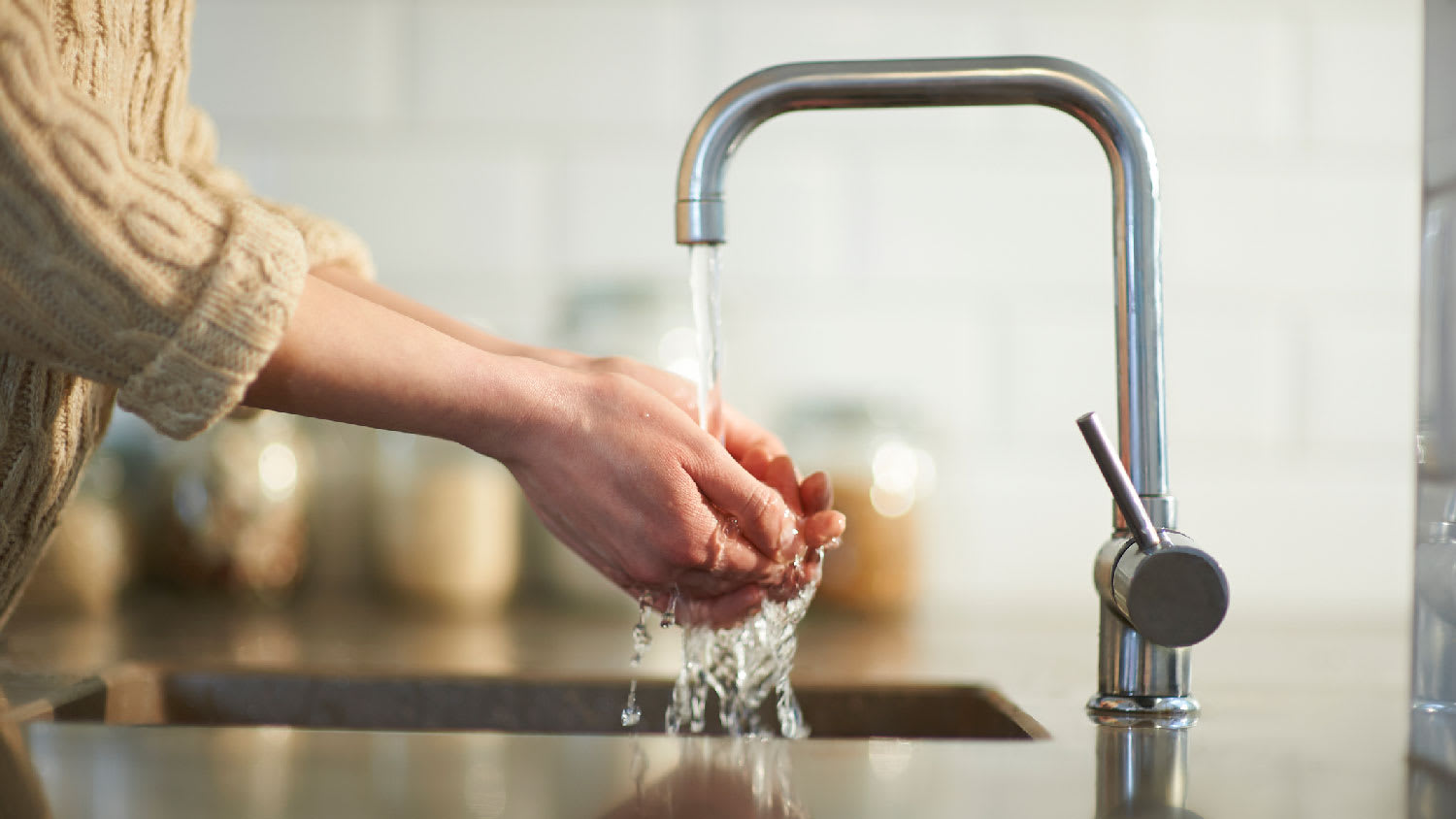 A woman washing her hands in the kitchen sink