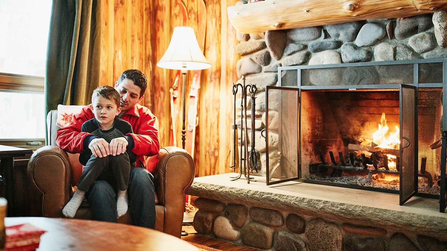 Father and son sitting by a stone fireplace