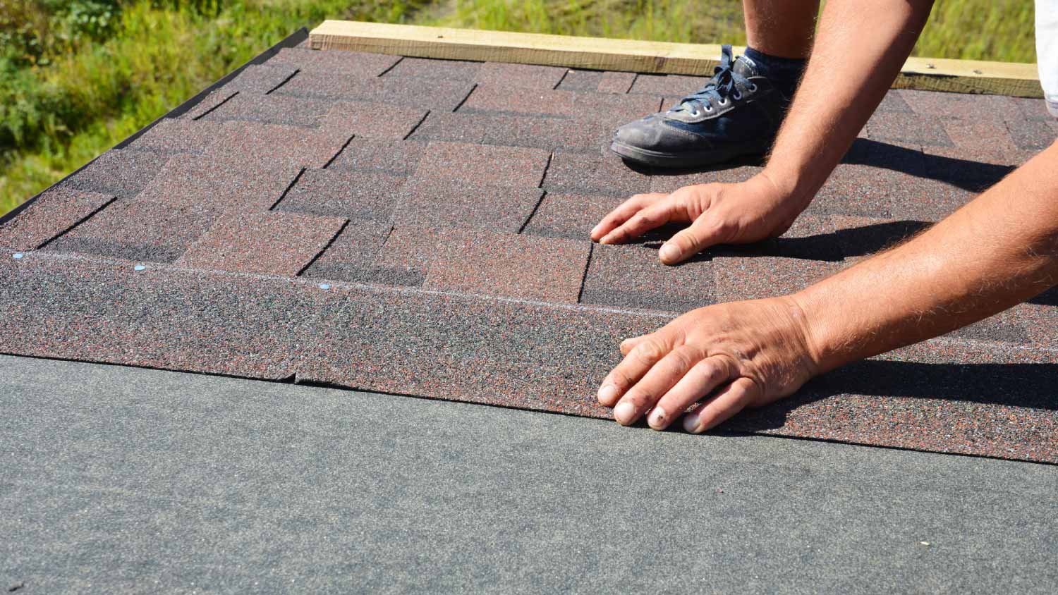Worker installing asphalt roof shingles