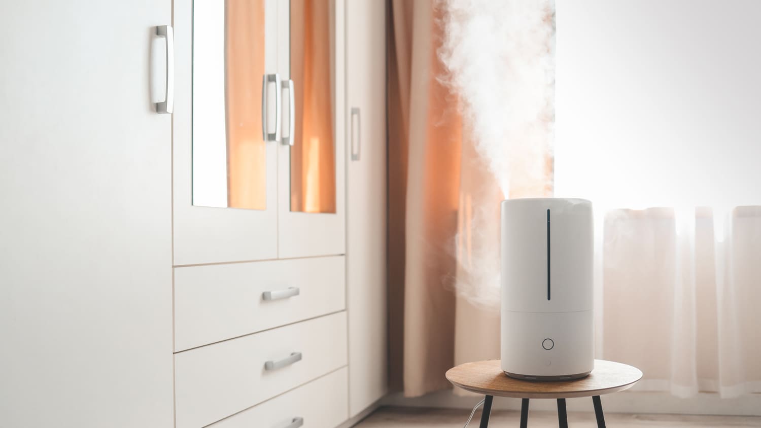 Modern air humidifier on table in bedroom
