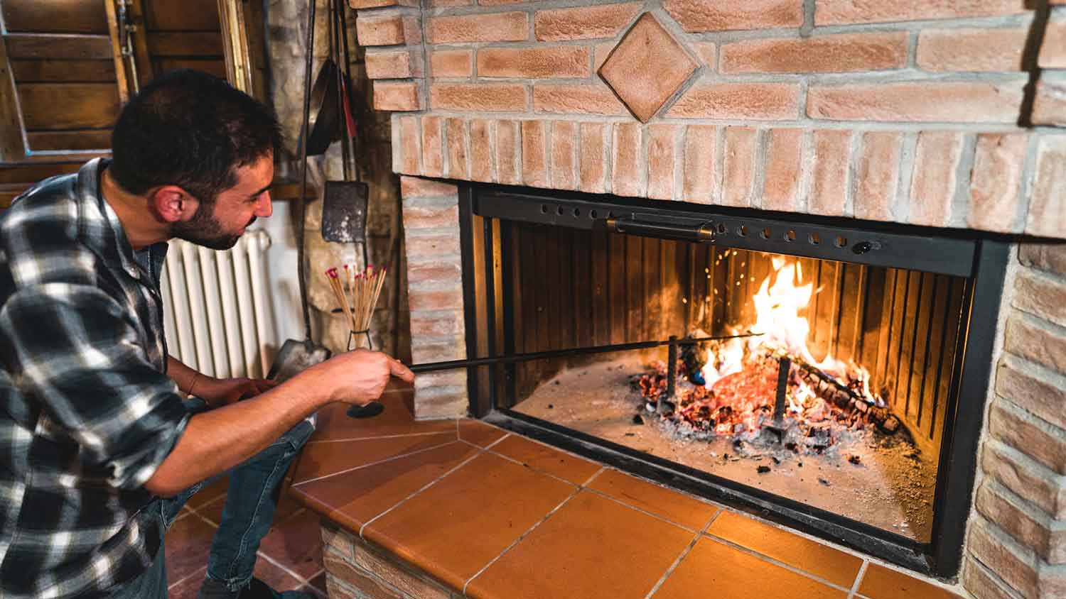 Man stoking the fire in a brick fireplace