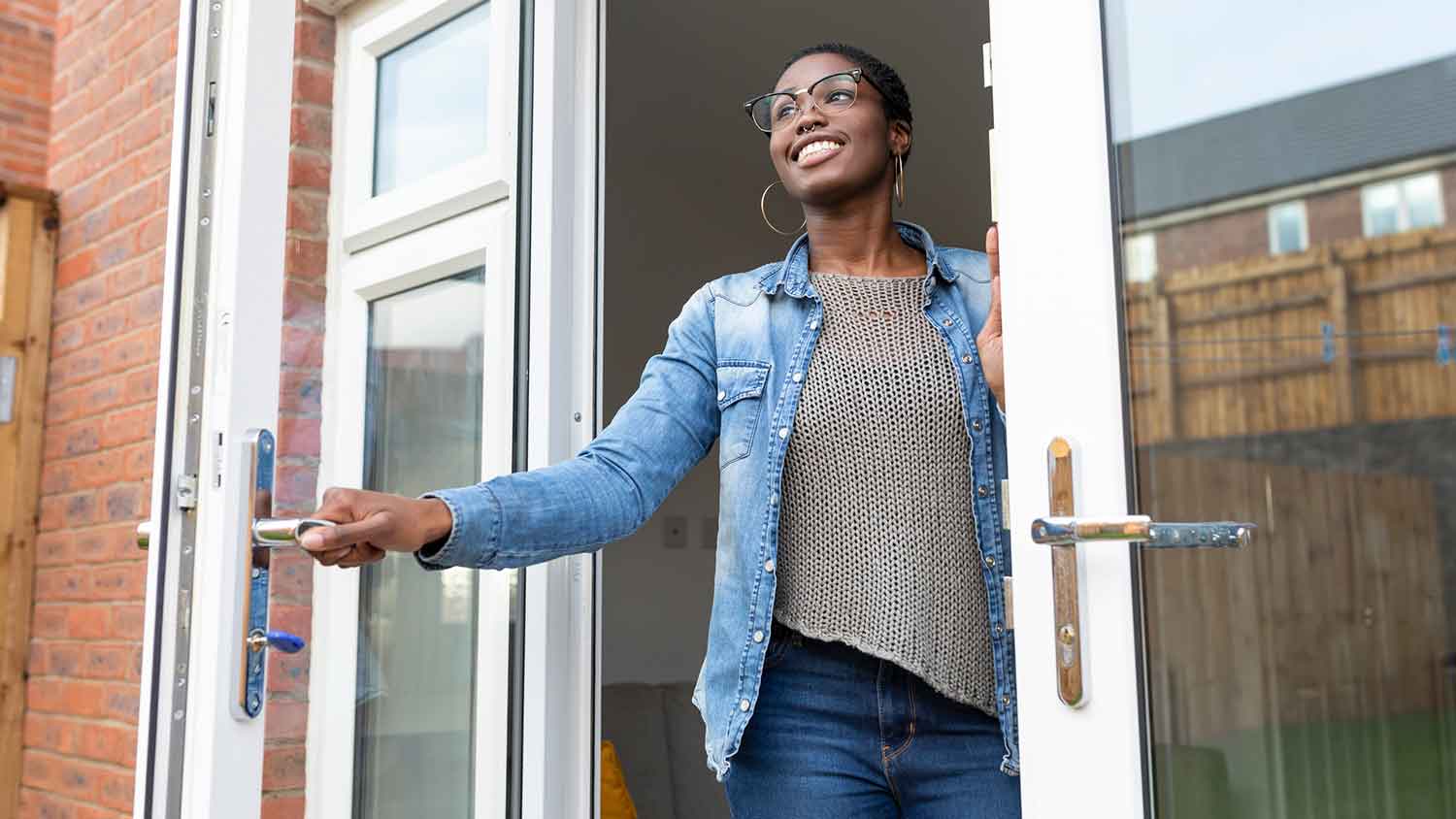 Smiling woman opening glass patio door