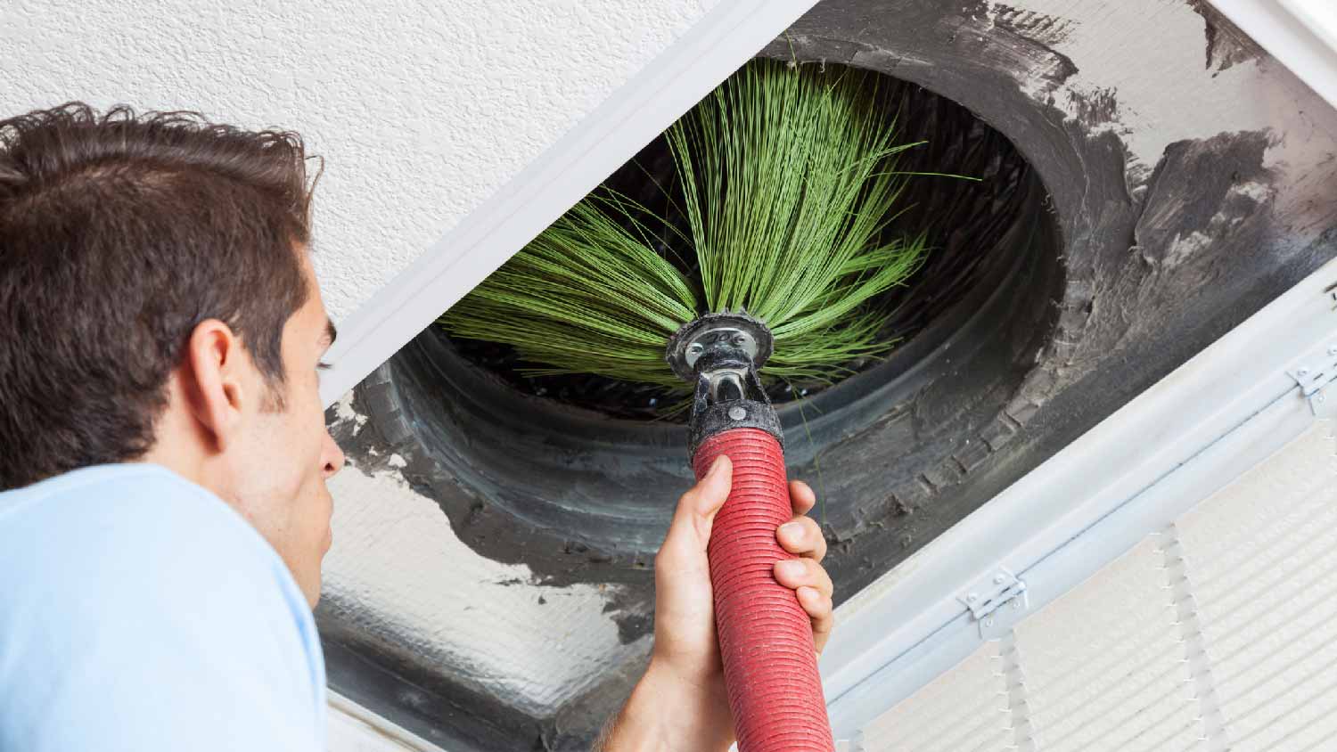 A professional vacuuming an air duct