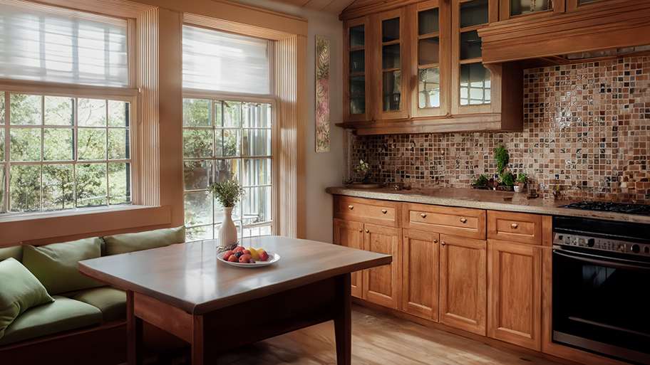 California kitchen according to AI, with warm Craftsman style wood cabinets, hand-made tile backsplash, and built-in banquette seating