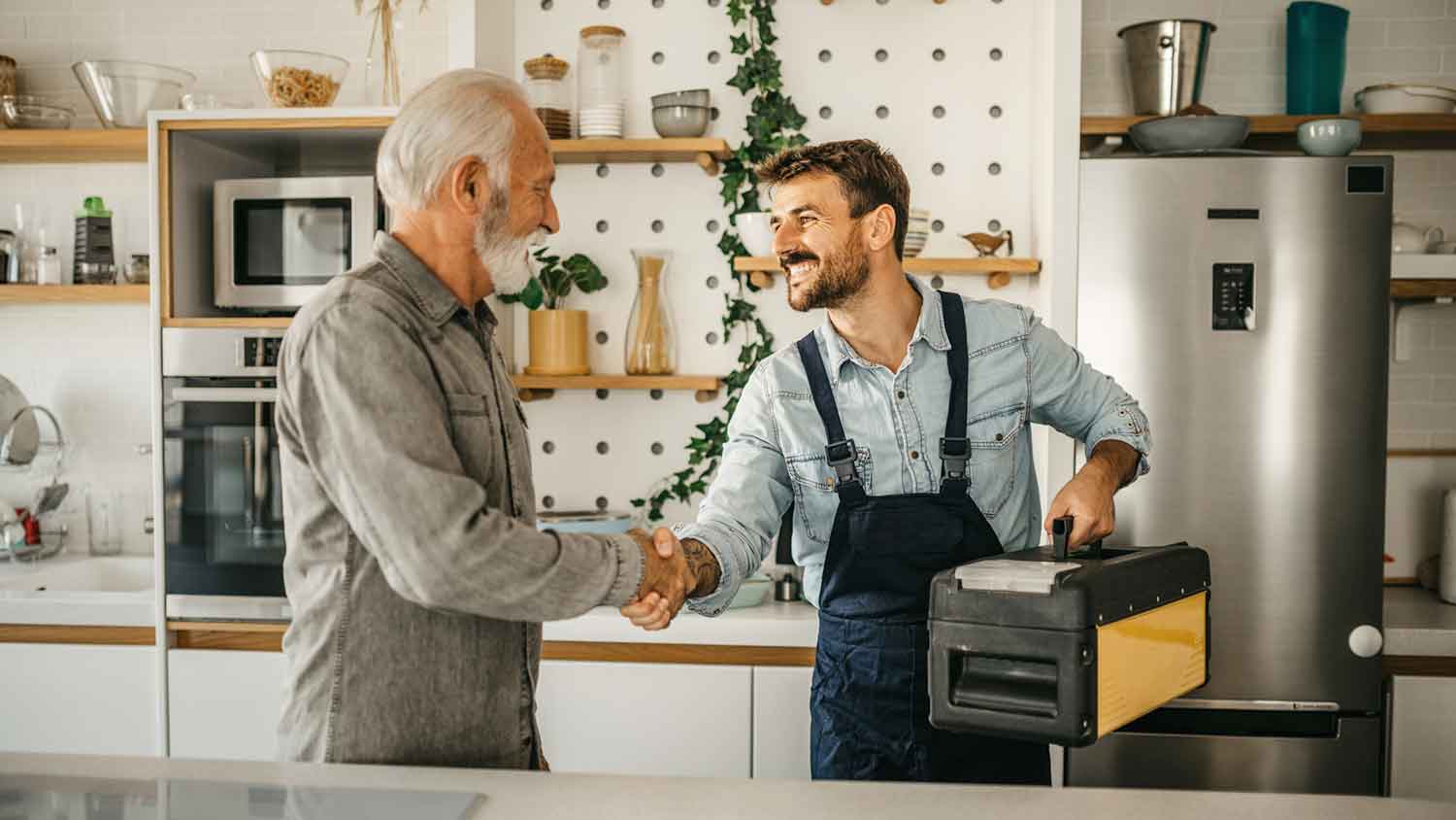 Happy client and plumber shaking hands in the kitchen