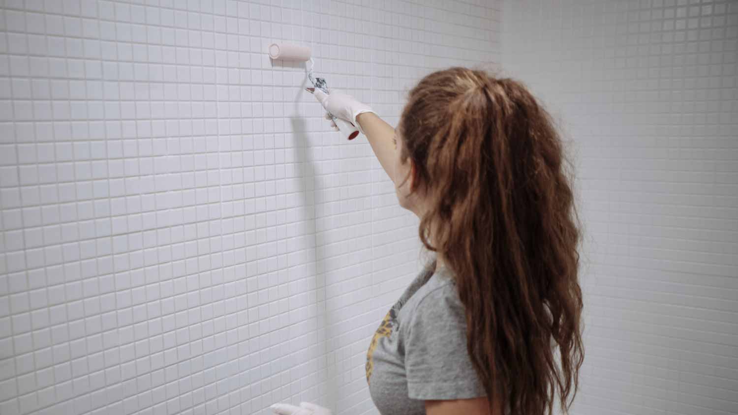 Woman painting her bathroom tiles