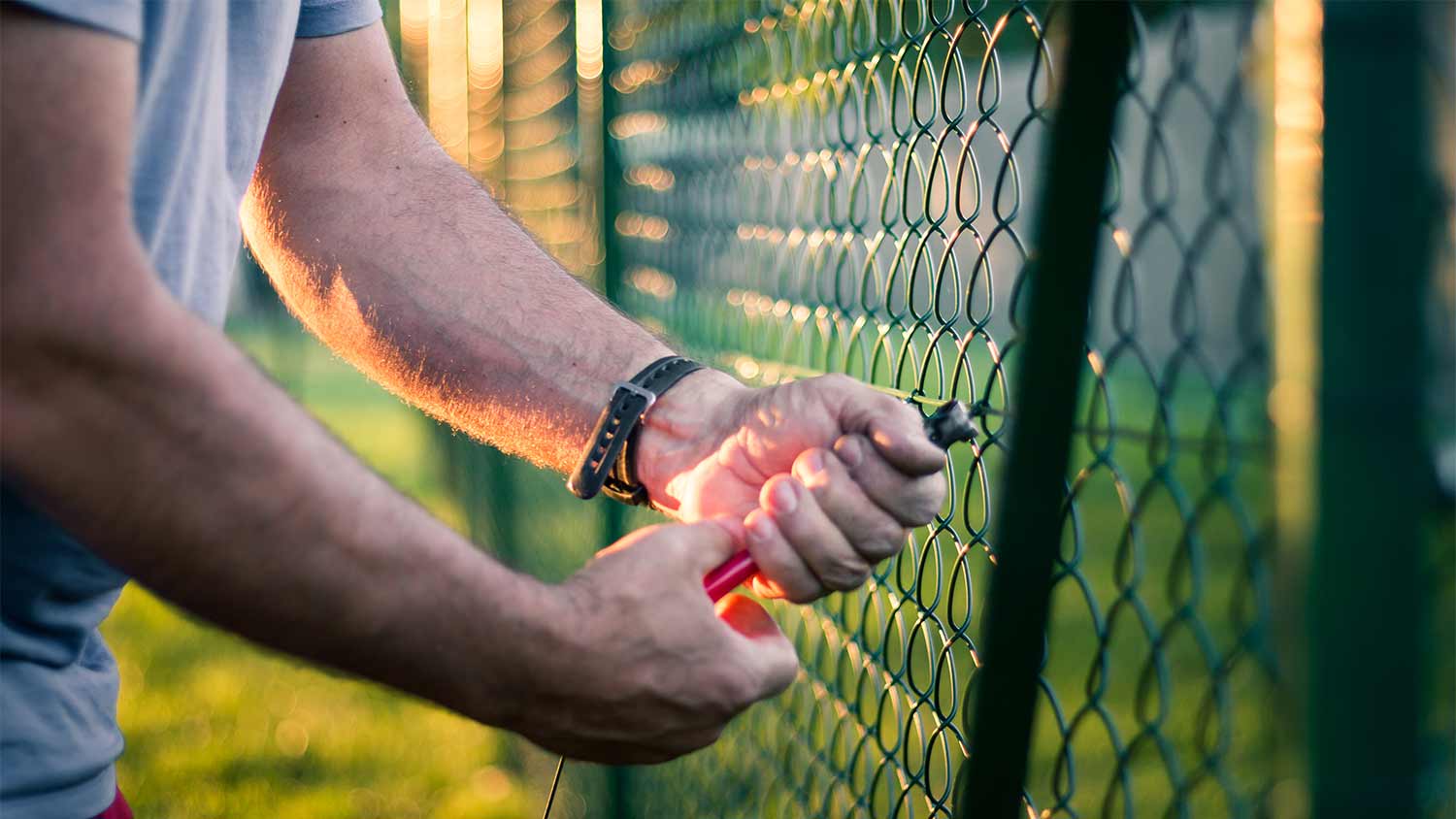 man using pliers on metal fence