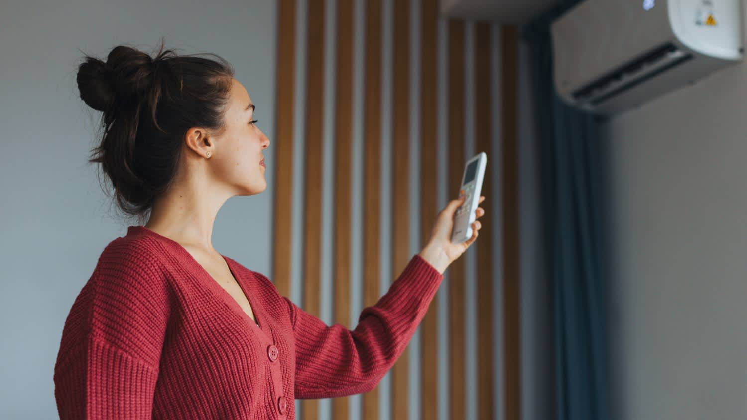 Woman adjusting temperature on air conditioner