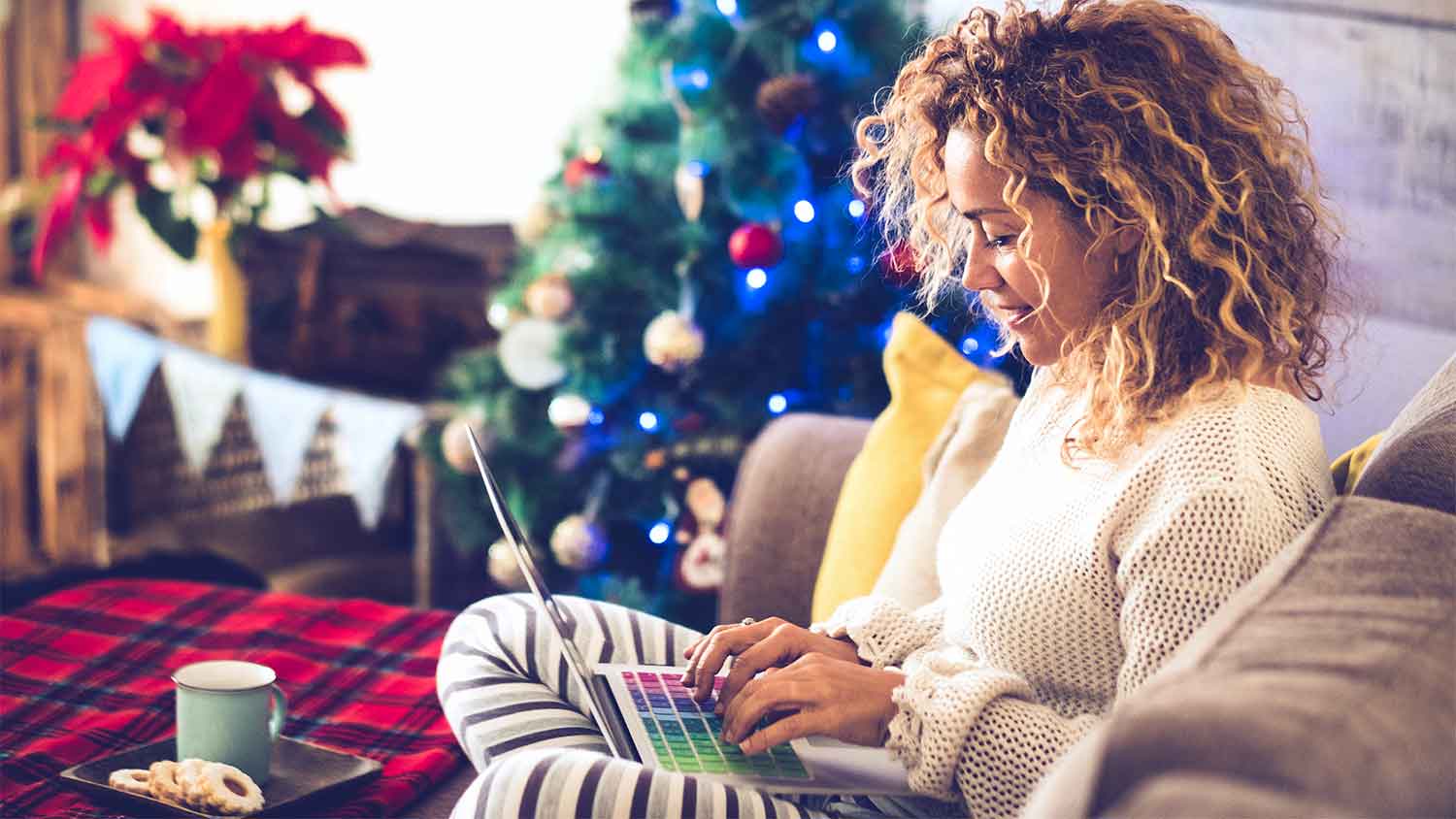 A woman uses her laptop with Christmas tree in the background