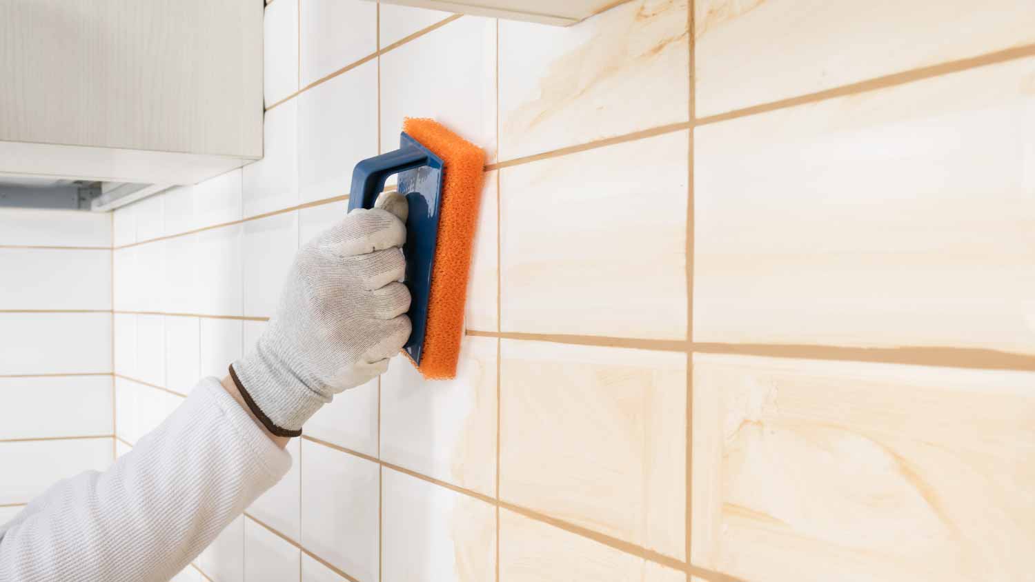 Man rubbing a brown grout