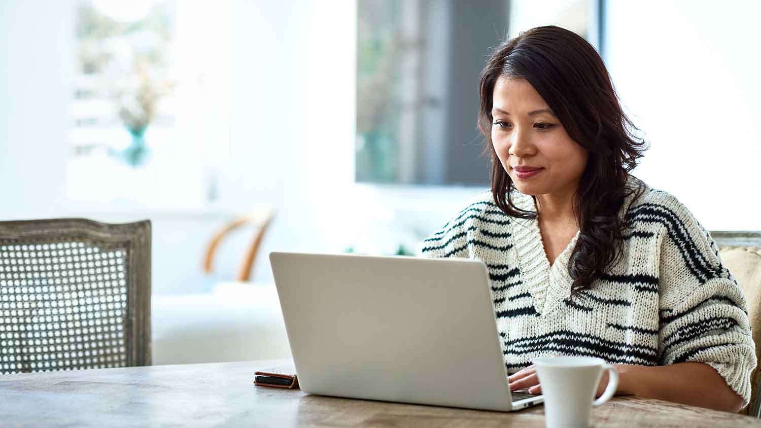 Woman in dining room using laptop to do some research