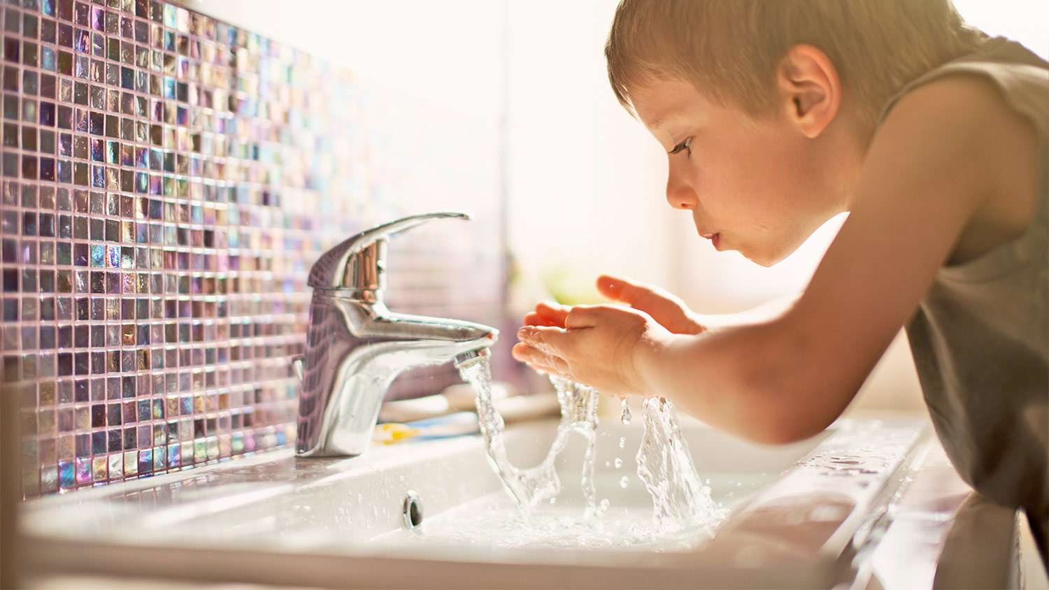 Boy washing hands in bathroom sink