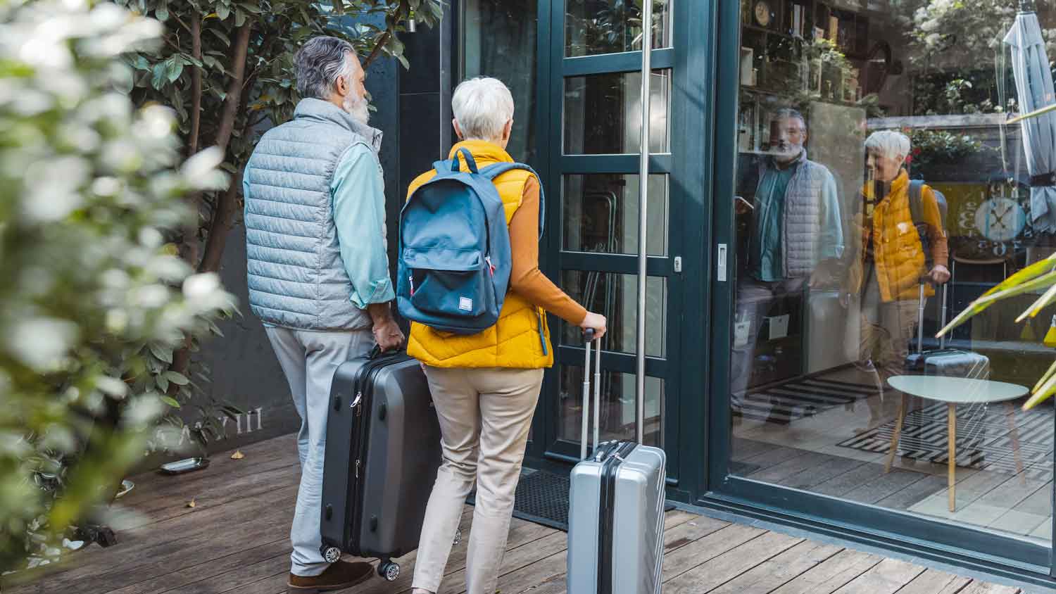 Senior couple with suitcases arriving to a guest house