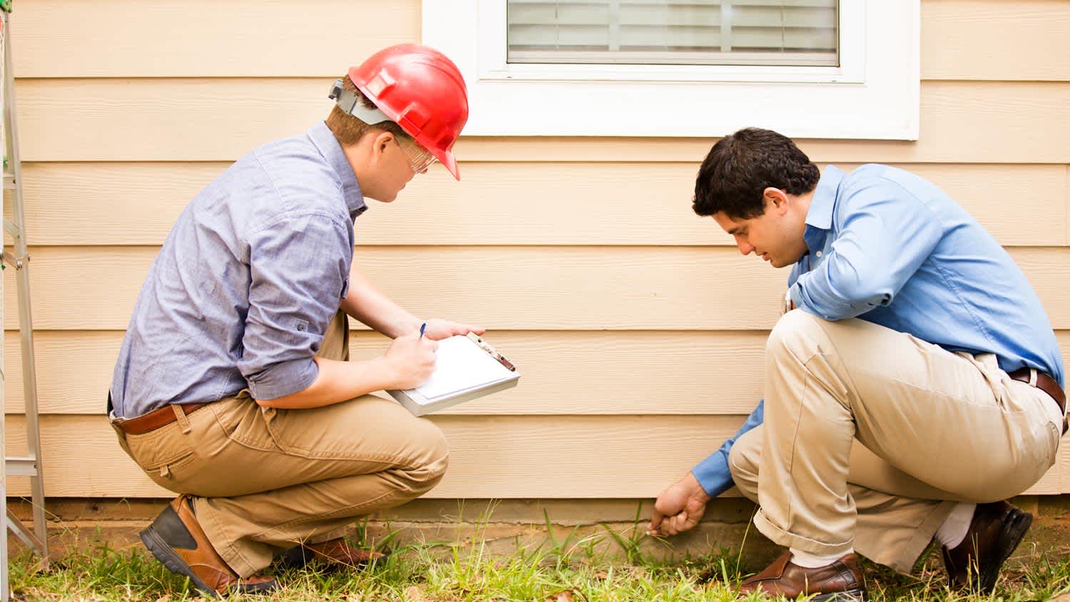 Two inspectors examining foundation of house
