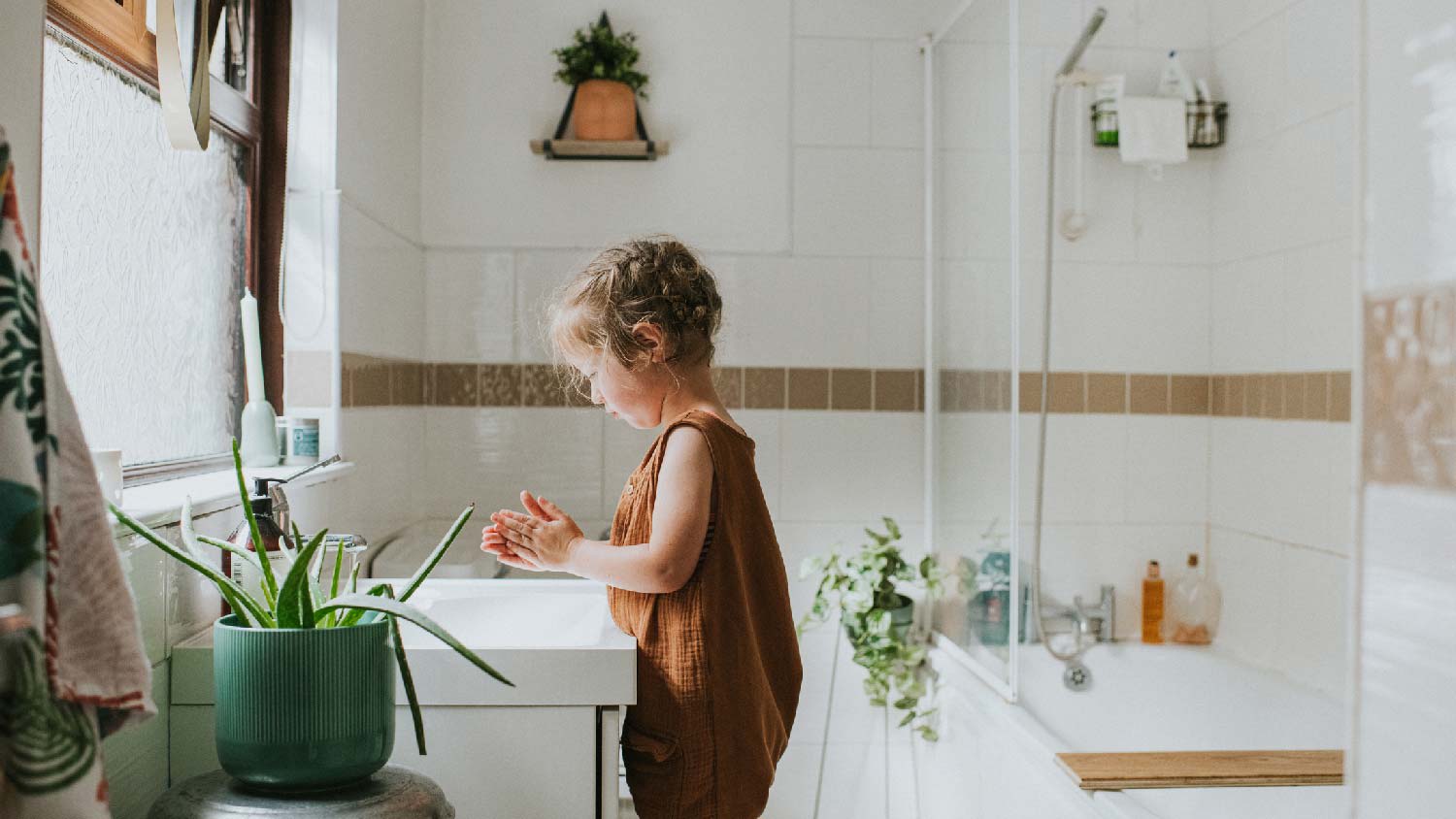 A little girl washing her hands in the bathroom sink
