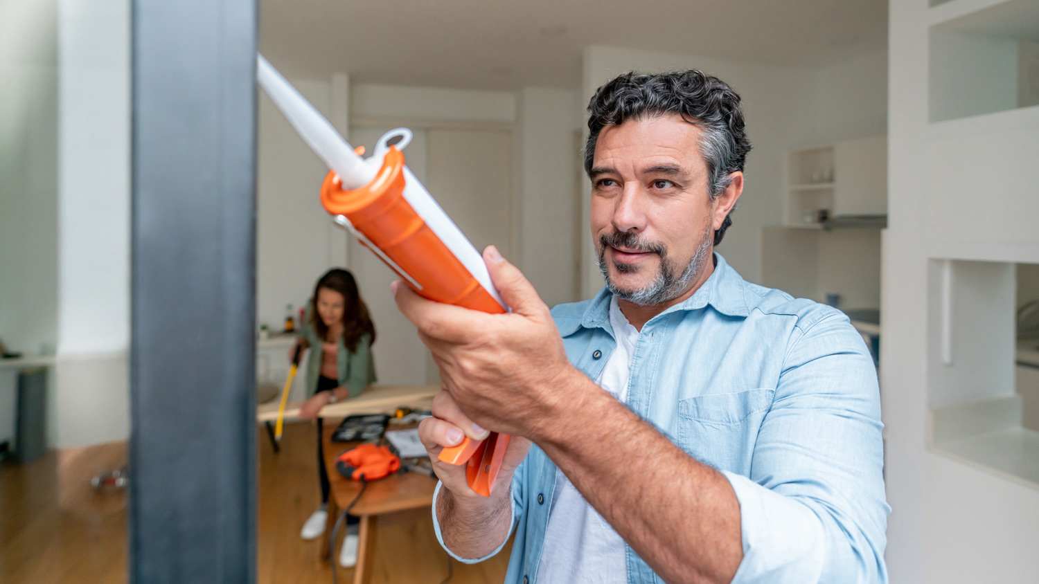 Man at home grouting his balcony door
