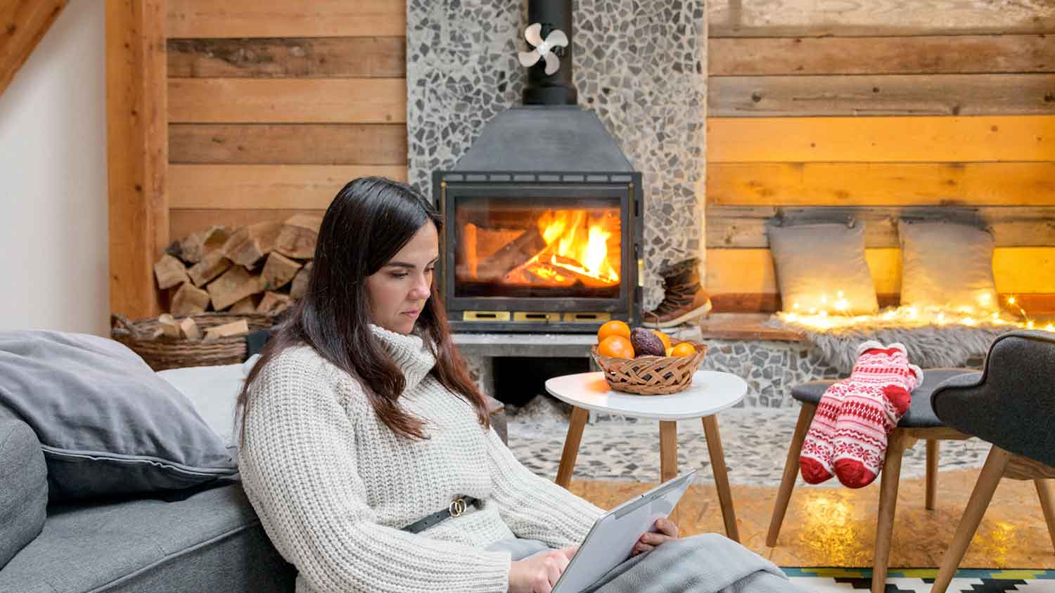 Woman sitting and using tablet next to a wood burning stove