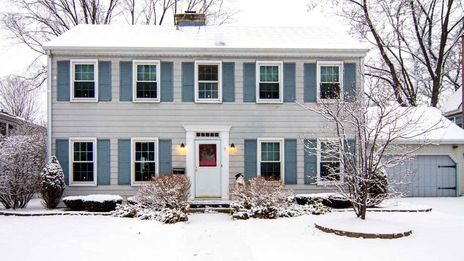 A two-story house with snow on its front yard