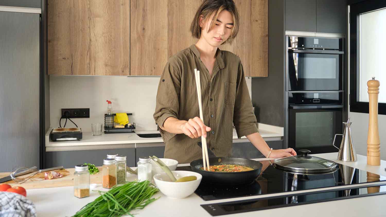 Young man using electric stove to cook dinner