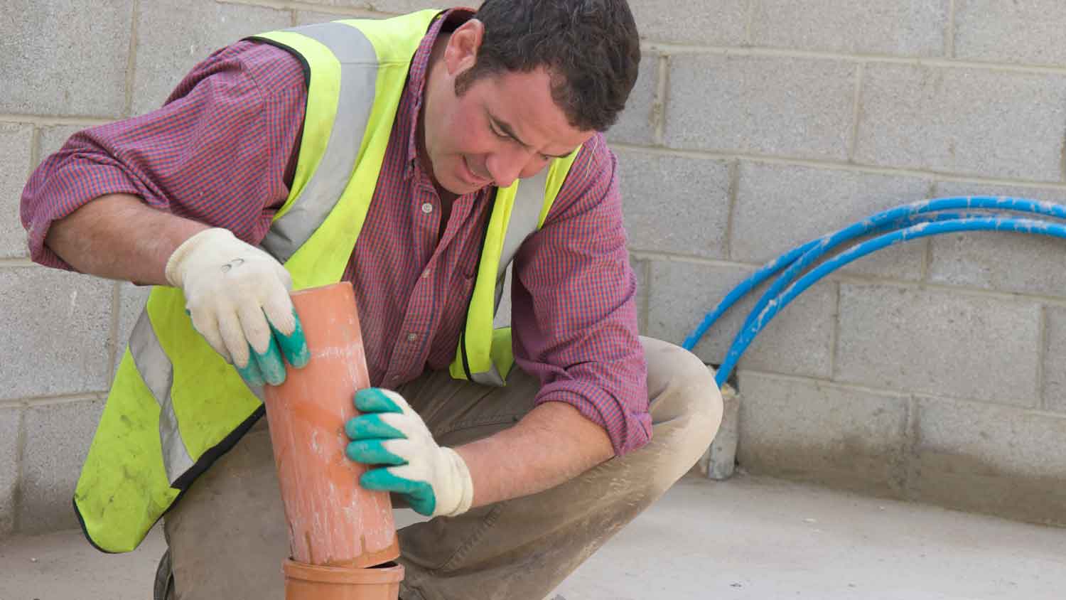 Plumber installing clay sewer pipe in a new construction