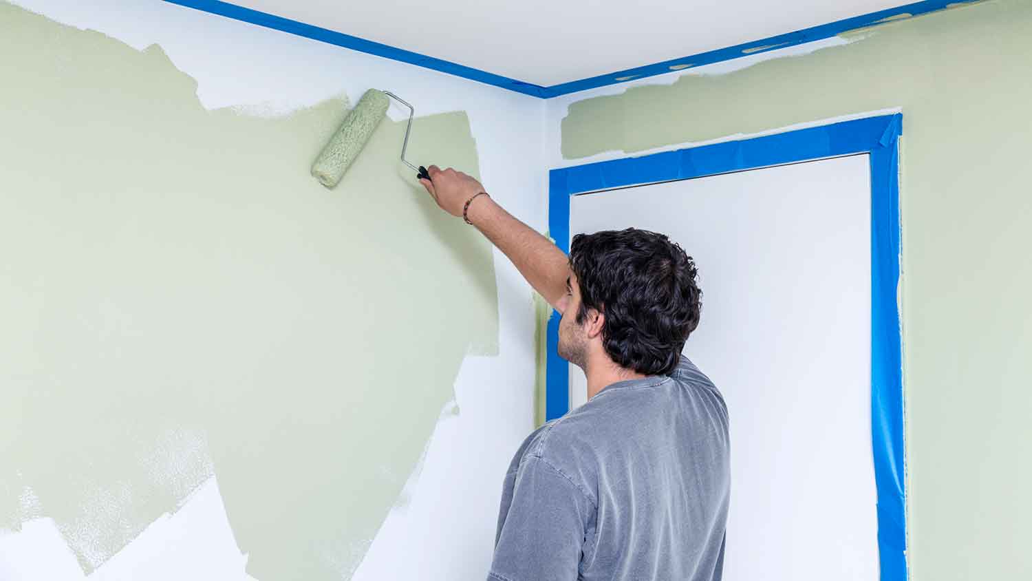 Young man using acrylic paint to paint a bedroom
