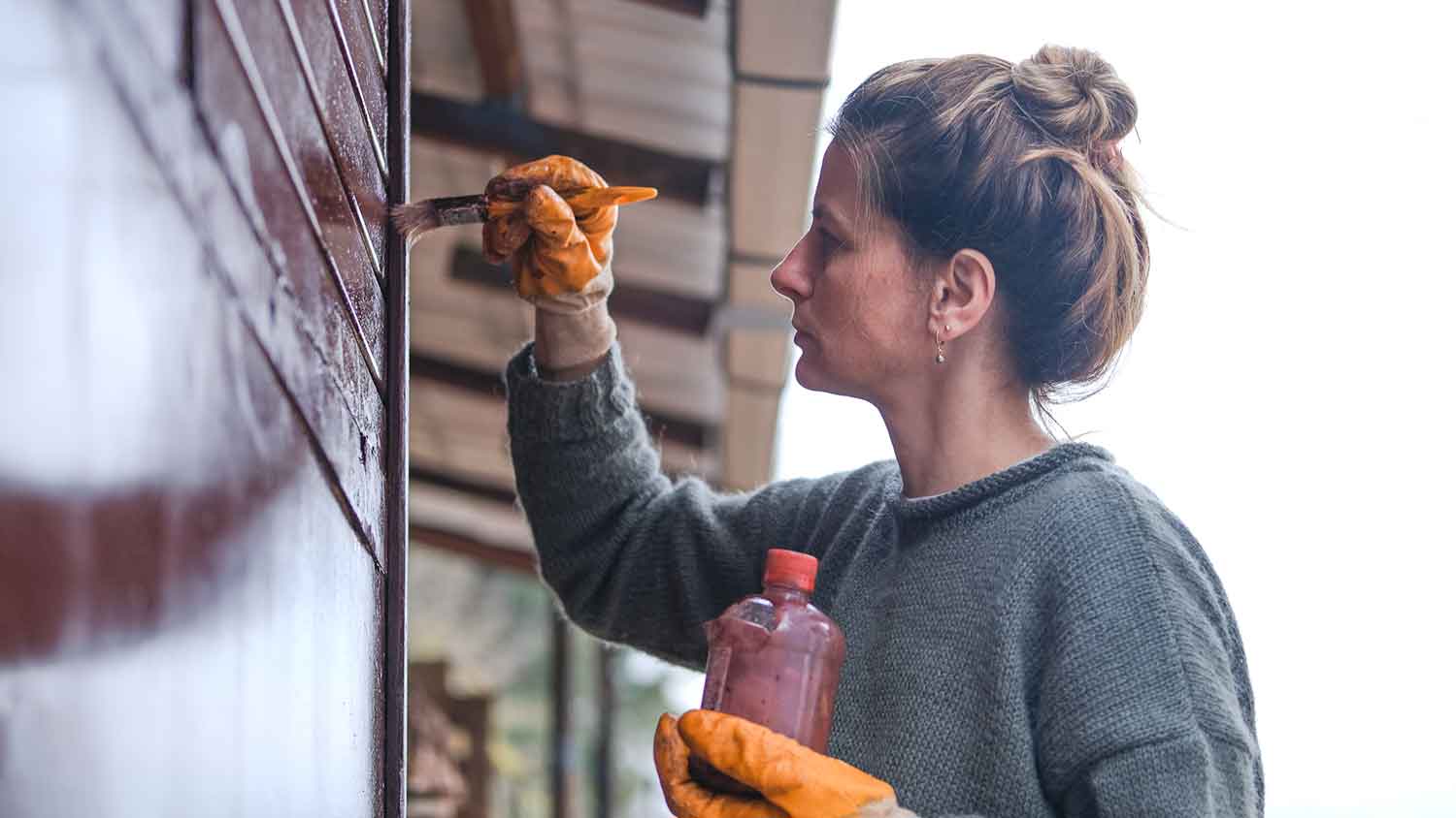 Woman using enamel paint to paint the house exterior
