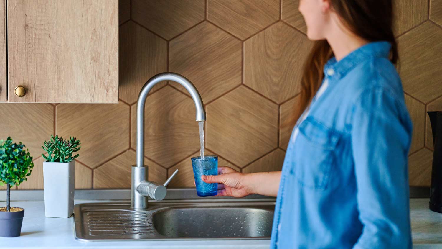woman pouring herself a glass of water from the faucet