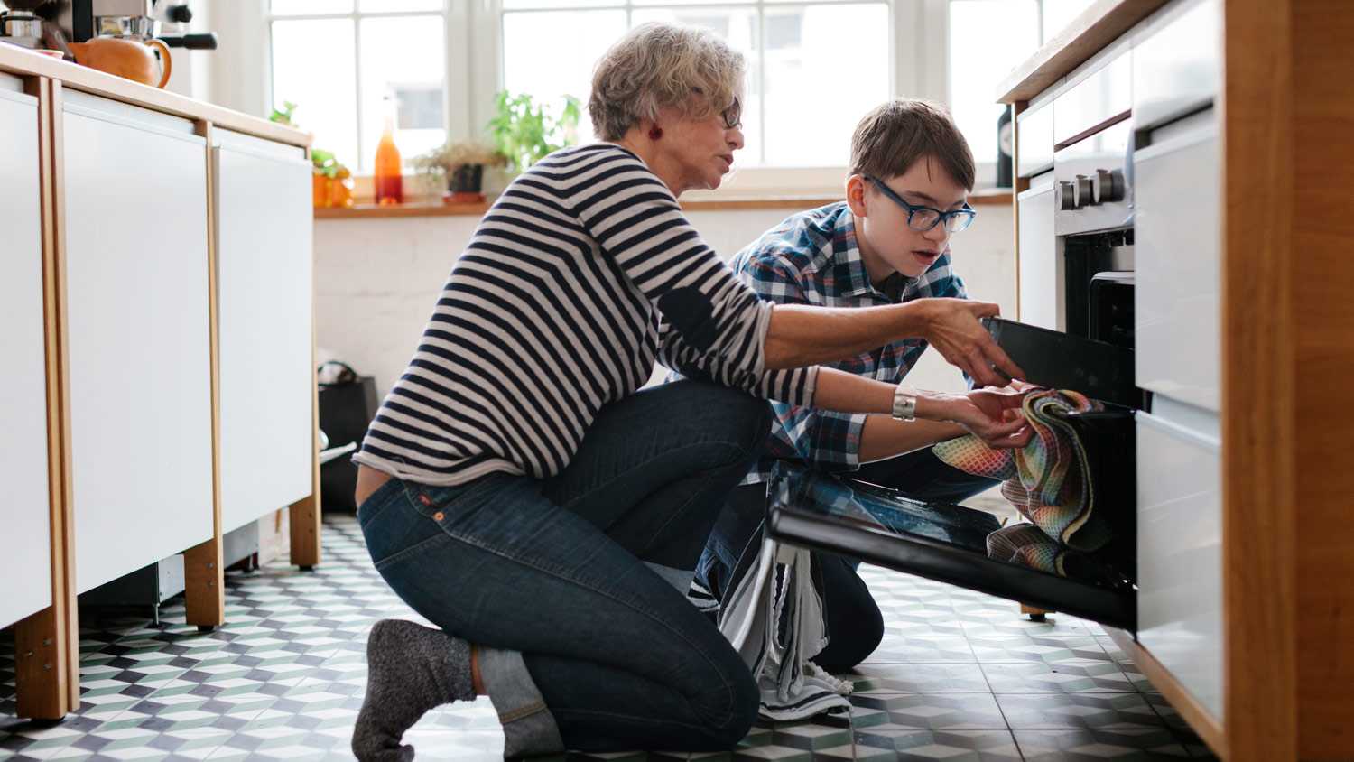 Mature Mother teaching her teenage Son how to bake