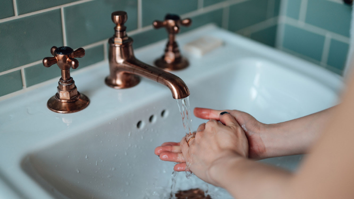 A woman washing her hands in front of a bathroom faucet
